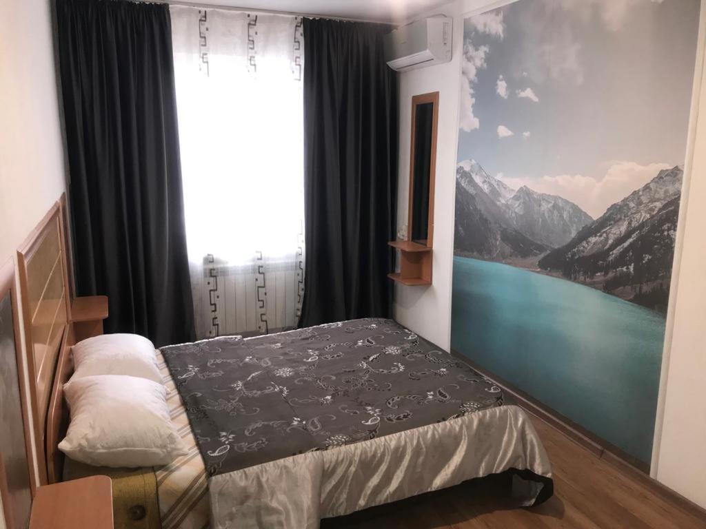 1 dormitorio con cama y ventana con vistas a las montañas en Apartments on Koktem 1, en Almaty