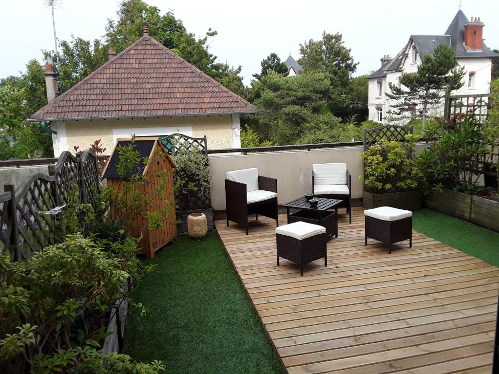 a backyard with a wooden deck with chairs and a table at ker Mamie in Merville-Franceville-Plage