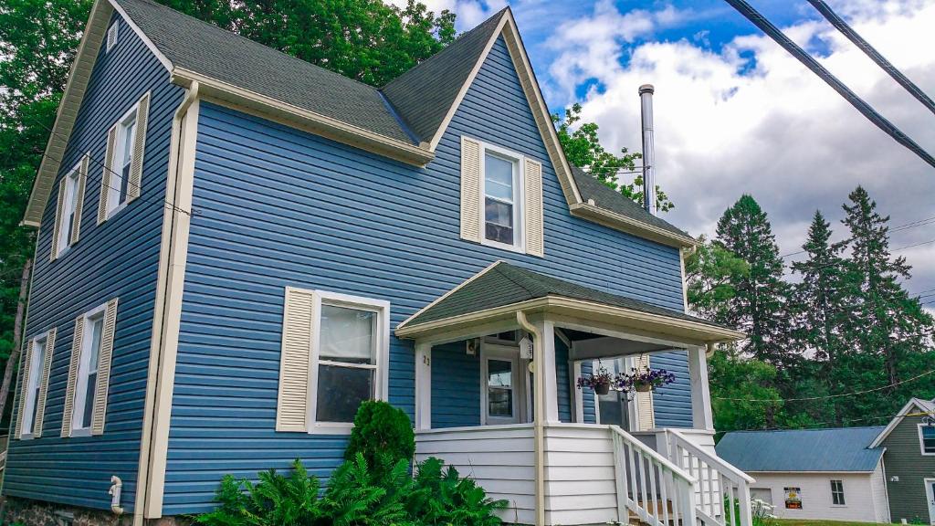 una casa azul con techo de gambrel en 23Maple en Haliburton