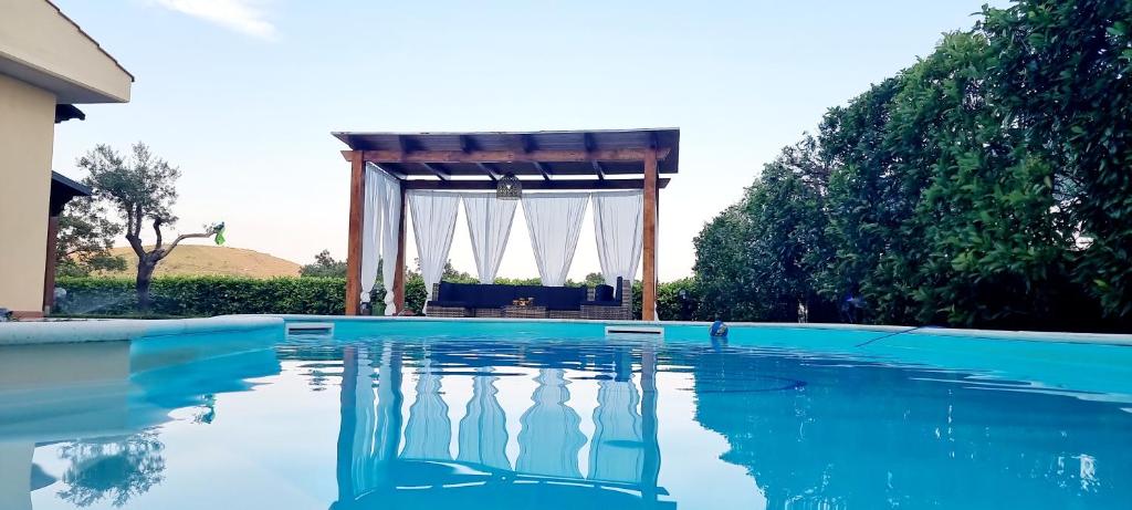 a swimming pool with a gazebo in the background at Villa Dolce Havana con piscina in Sperlonga