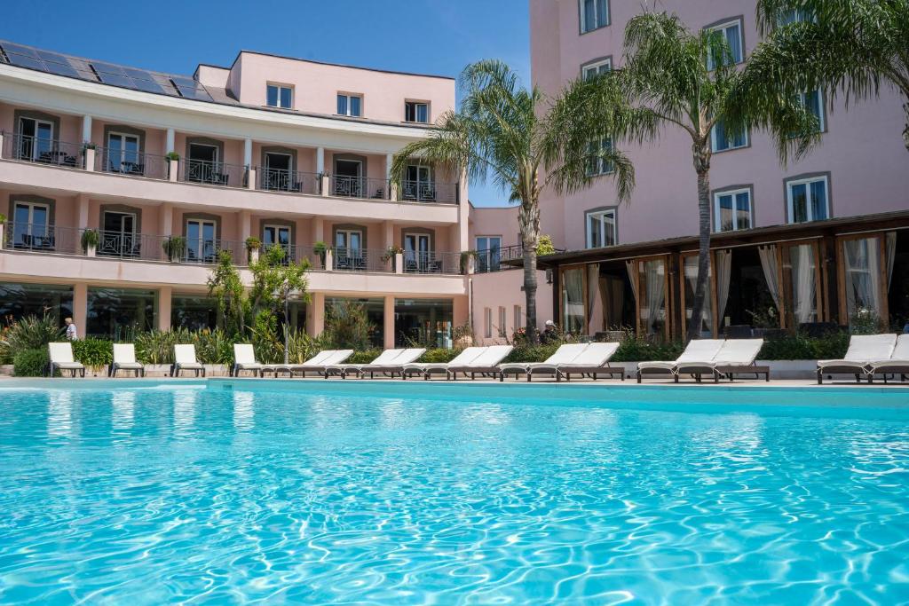 a swimming pool in front of a building at Hotel Isola Sacra Rome Airport in Fiumicino