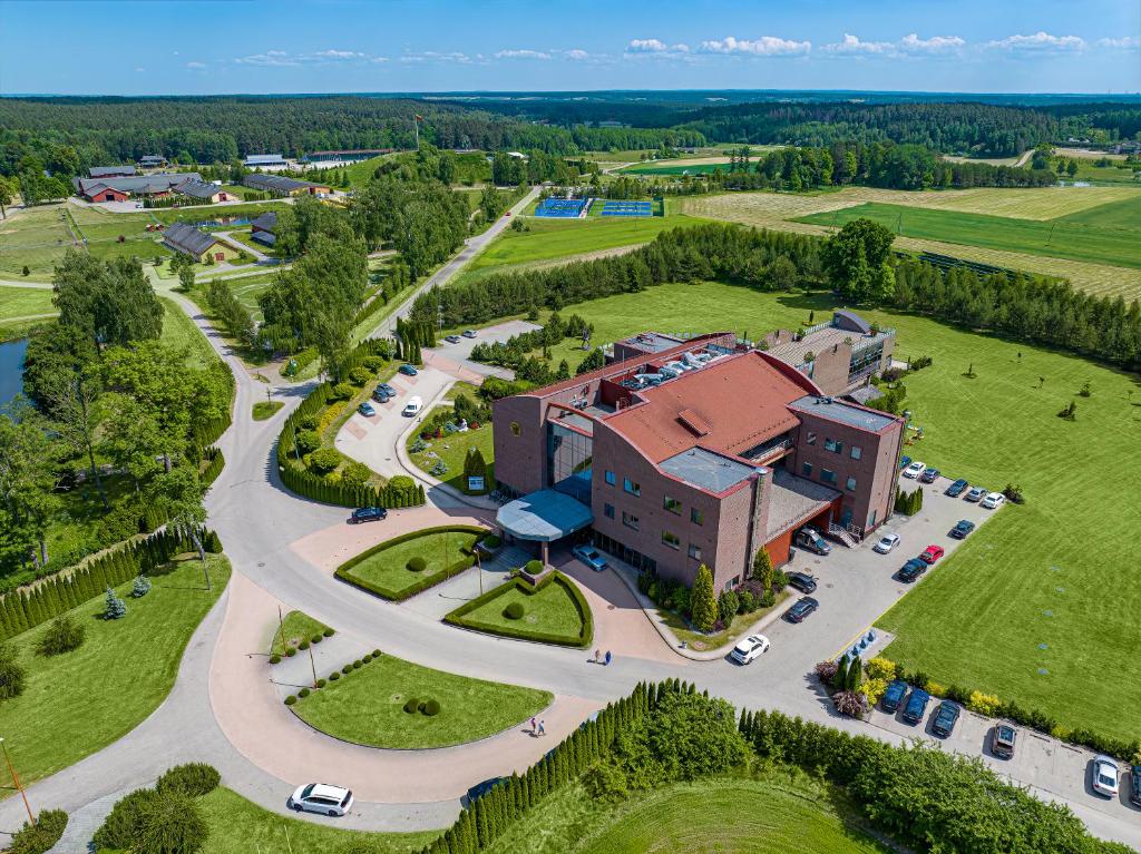 una vista aérea de un edificio con coches aparcados en un parque en Harmony Park Hotel & SPA, en Prienai