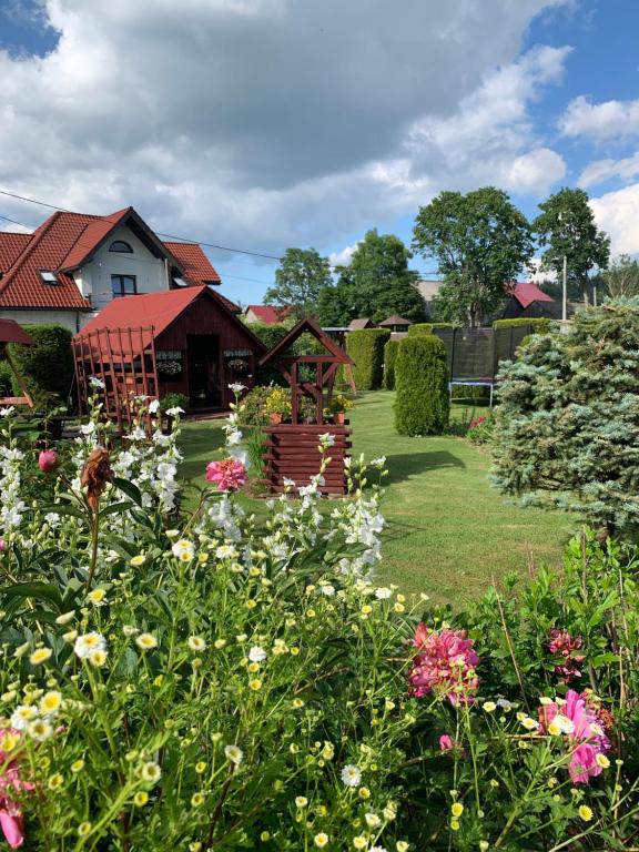 a garden with flowers in front of a house at Agroturystyka Pod Dzwonnicą in Zubrzyca Górna