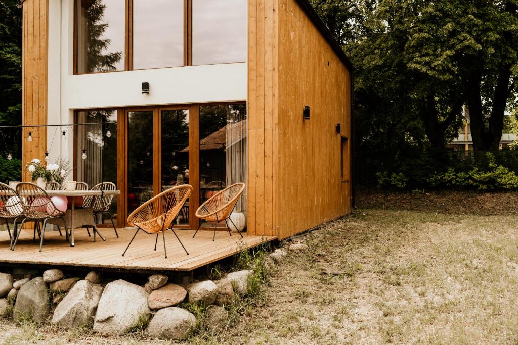 a wooden deck with chairs and a table in front of a house at Domek Discovery Mazury in Mrągowo