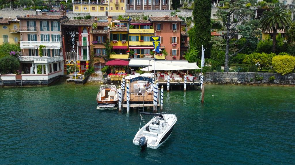 due barche sono ormeggiate in un molo in acqua di Hotel Baia D'Oro - Adults Only a Gargnano