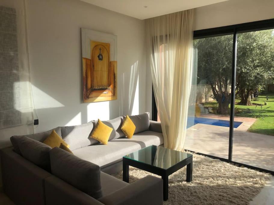Pavillon avec piscine privée - AL MAADEN Marrakech في مراكش: غرفة معيشة مع أريكة وطاولة