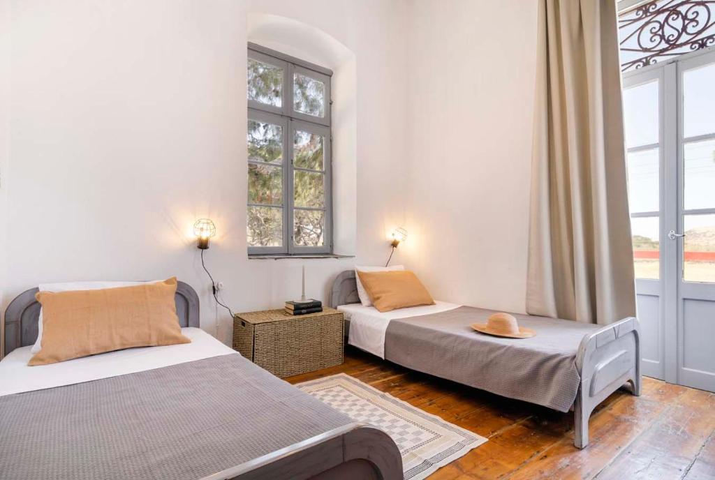 two beds in a room with two windows at Villa Gaia - Traditional Stone Villa in Rózia