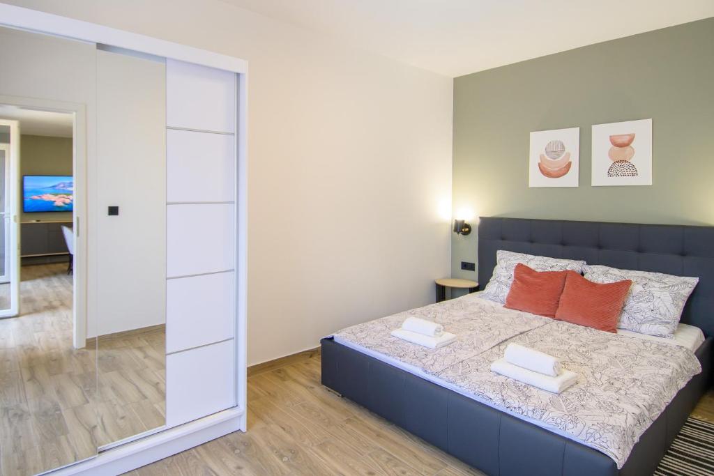 a bedroom with a bed with orange pillows and a mirror at Apartments & Rooms Darrer in Poreč