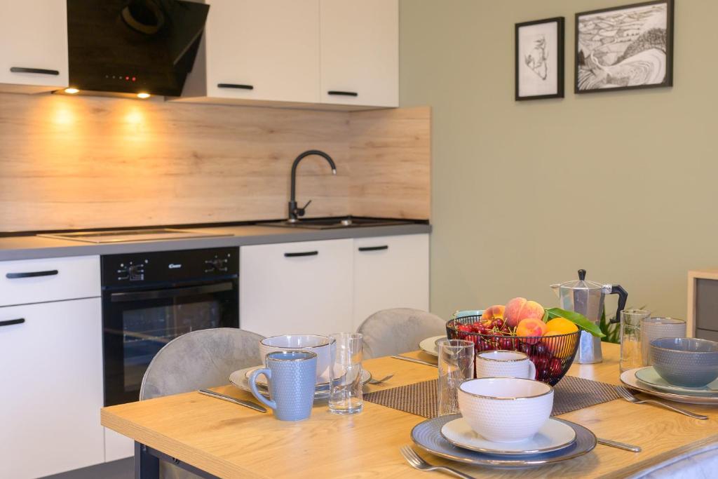 a kitchen with a wooden table with plates and bowls at Apartments & Rooms Darrer in Poreč