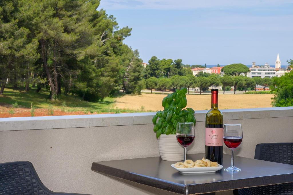 a table with a bottle of wine and two glasses at Apartments & Rooms Darrer in Poreč