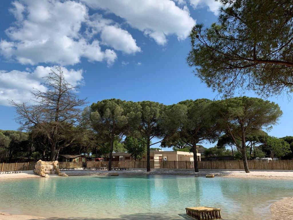 una grande piscina d'acqua con alberi sullo sfondo di Camping la Tamarissière ad Agde