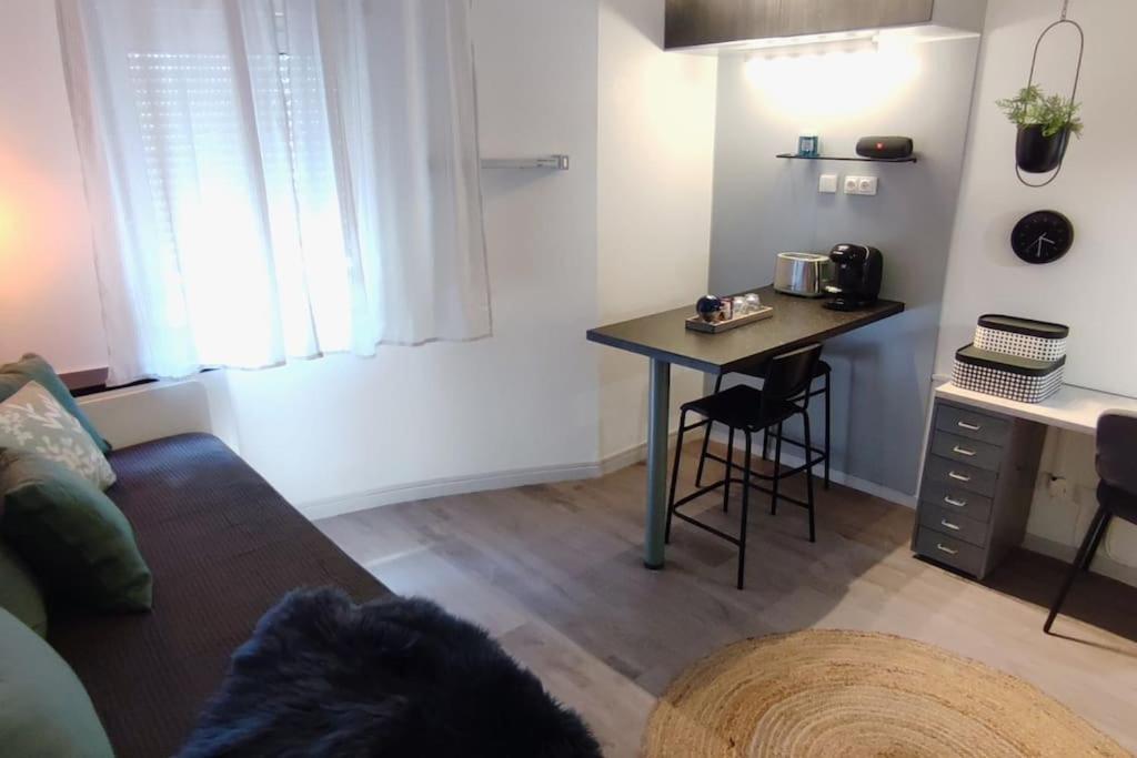 ein Wohnzimmer mit einem Sofa und einem Tisch sowie eine Küche in der Unterkunft STUDCLUB studio climatisé confortable face tram parking in Juvignac