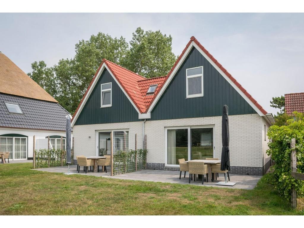 a house with a green roof with tables and chairs at Bungalow on Texel with a spacious terrace in De Cocksdorp