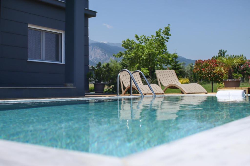 a group of chairs sitting next to a swimming pool at Zeusplace Pool Villa Olympus Riviera in Litochoro