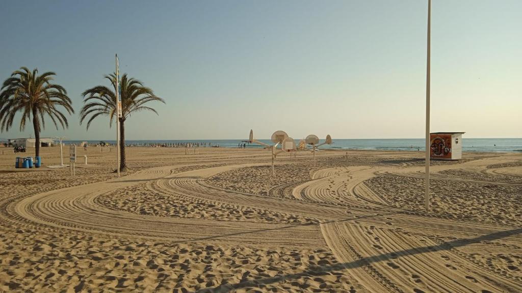 a sandy beach with palm trees and the ocean at Apartamento Bonanza, Playa de Gandía in Los Mártires