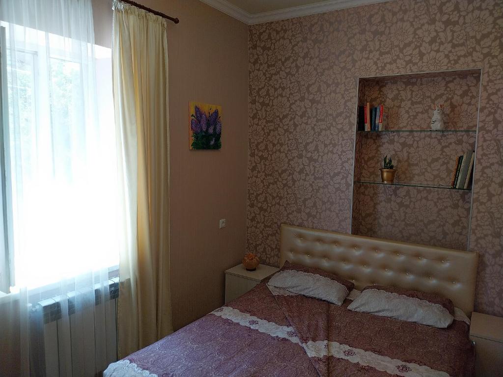 a bedroom with a bed and a window and a mirror at Like Home Guesthouse in Yerevan