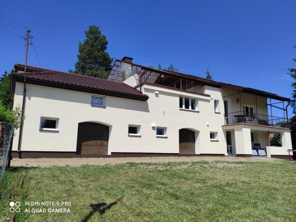 a large white house with a large yard at Agroturystyka Huta in Krzywe