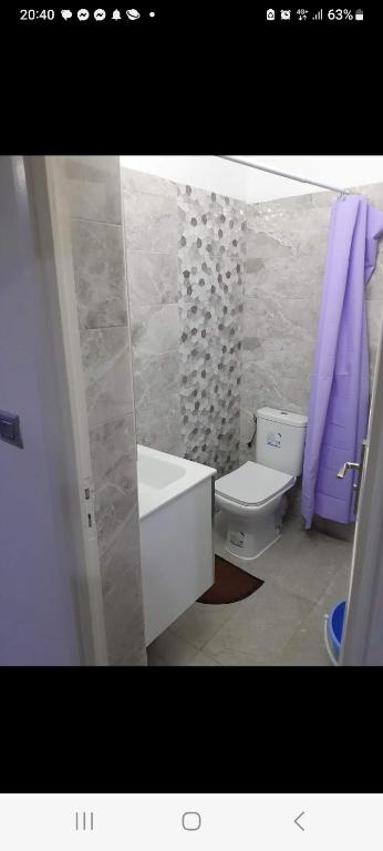 La salle de bains est pourvue d'une baignoire, de toilettes et de serviettes pourpres. dans l'établissement Residence djerba 3, à Houmt Souk