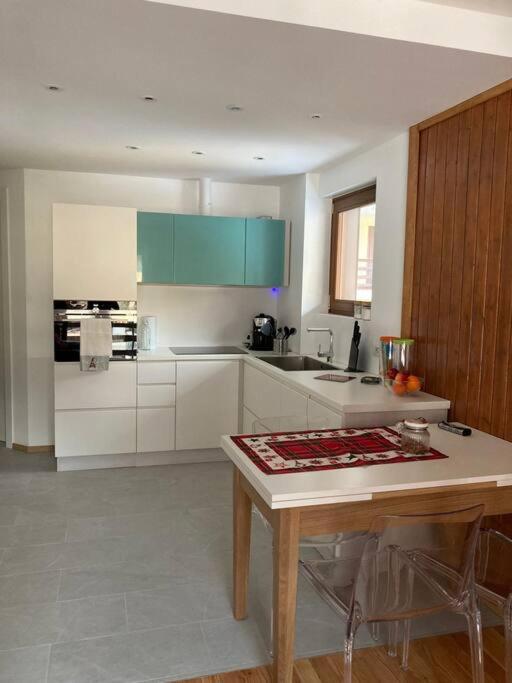 a kitchen with white cabinets and a table in it at Miri Apartment in Alagna Valsesia