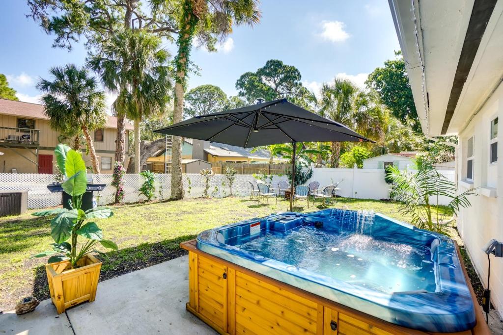 una bañera de hidromasaje en un patio trasero con sombrilla en Port Richey Home with Private Hot Tub Pets Welcome!, en Port Richey