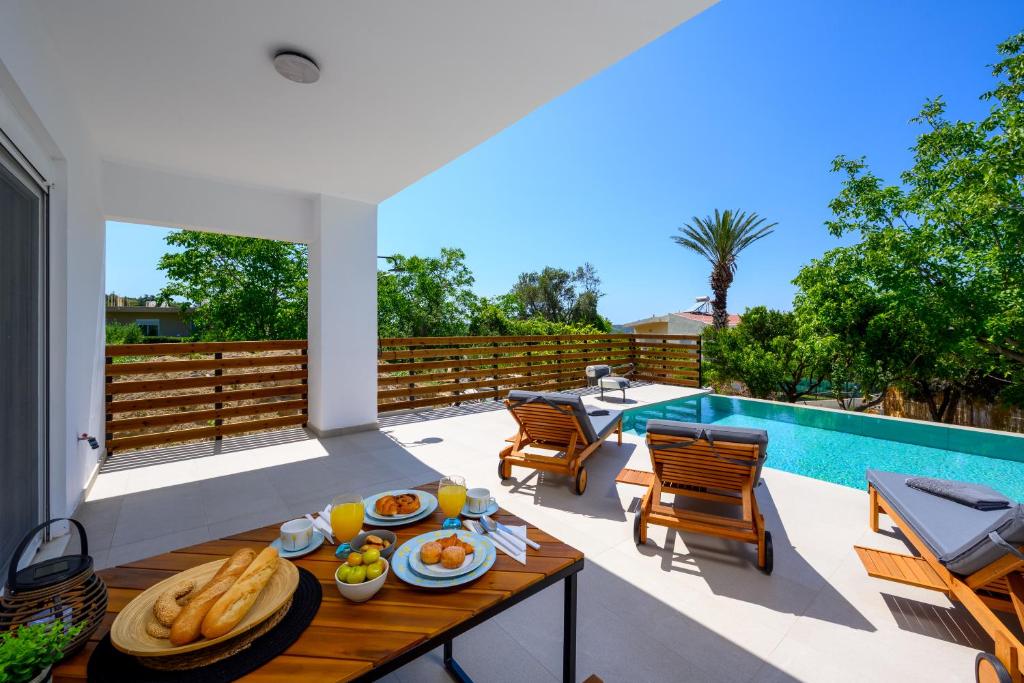 a patio with a table with food on it next to a pool at Aelia Luxury Villa in Sálakos
