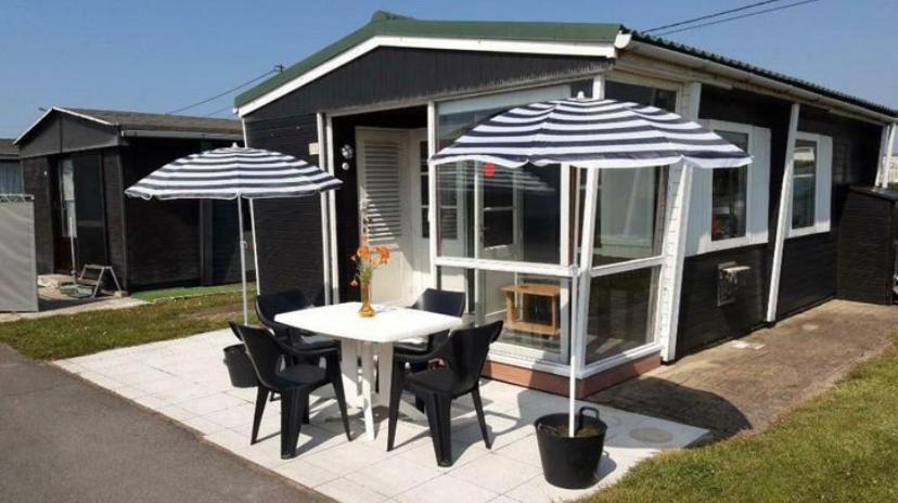 un patio con mesa y 2 sombrillas en Vacation house MAX for 4 persons, 350 m from the sea, in Pollentier Middelkerke Park en Middelkerke