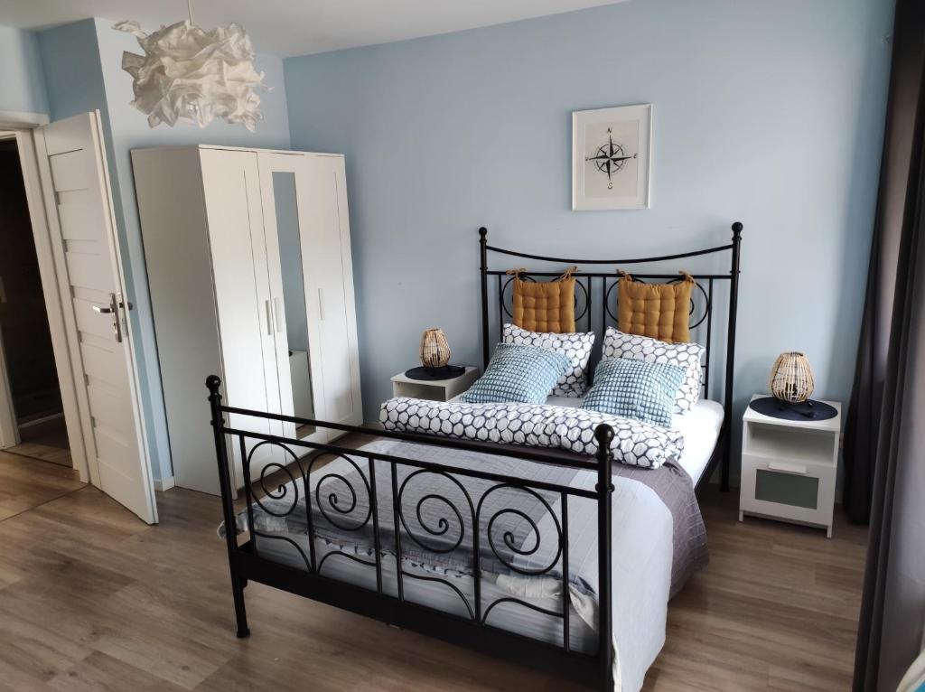 a bedroom with a black bed with blue and white pillows at Apartamenty Przy Wydmie in Rowy