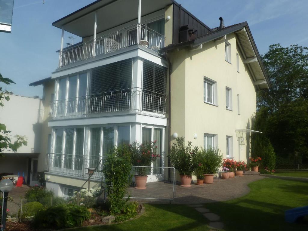 a large white building with a balcony and potted plants at Gästezimmer Suppan in Hörbranz