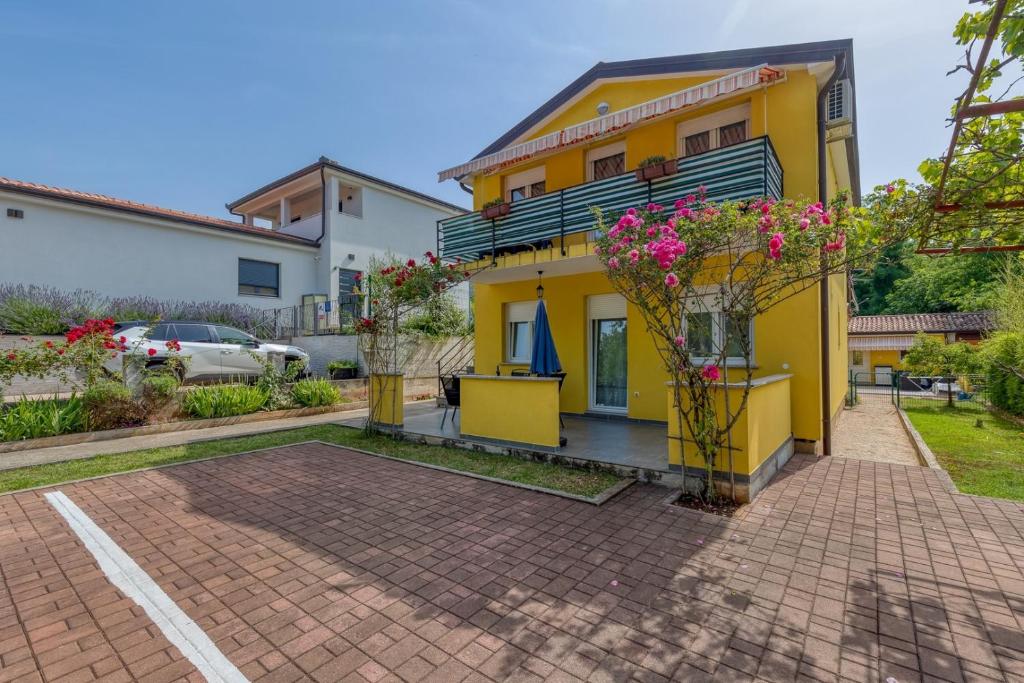 a yellow house with flowers in a courtyard at Mara in Umag