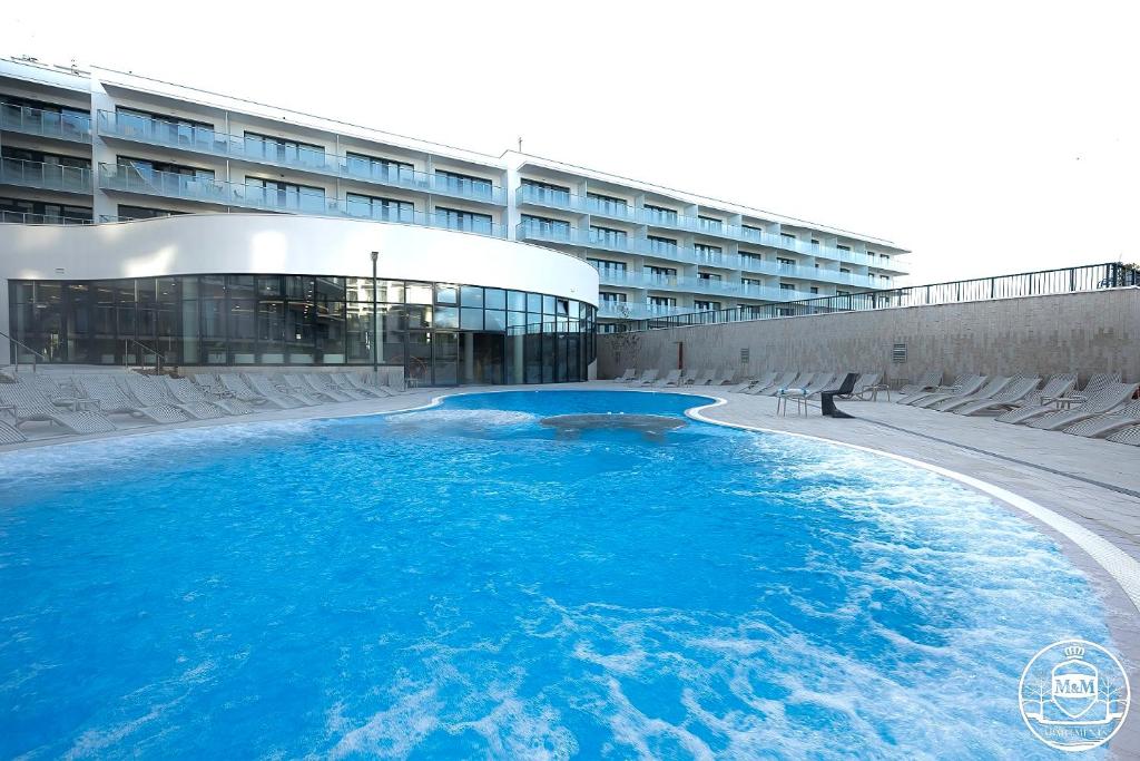 een groot zwembad met blauw water voor een gebouw bij Polanki Aqua - Aquapark, Free Parking, Apartments M&M Kołobrzeg in Kołobrzeg