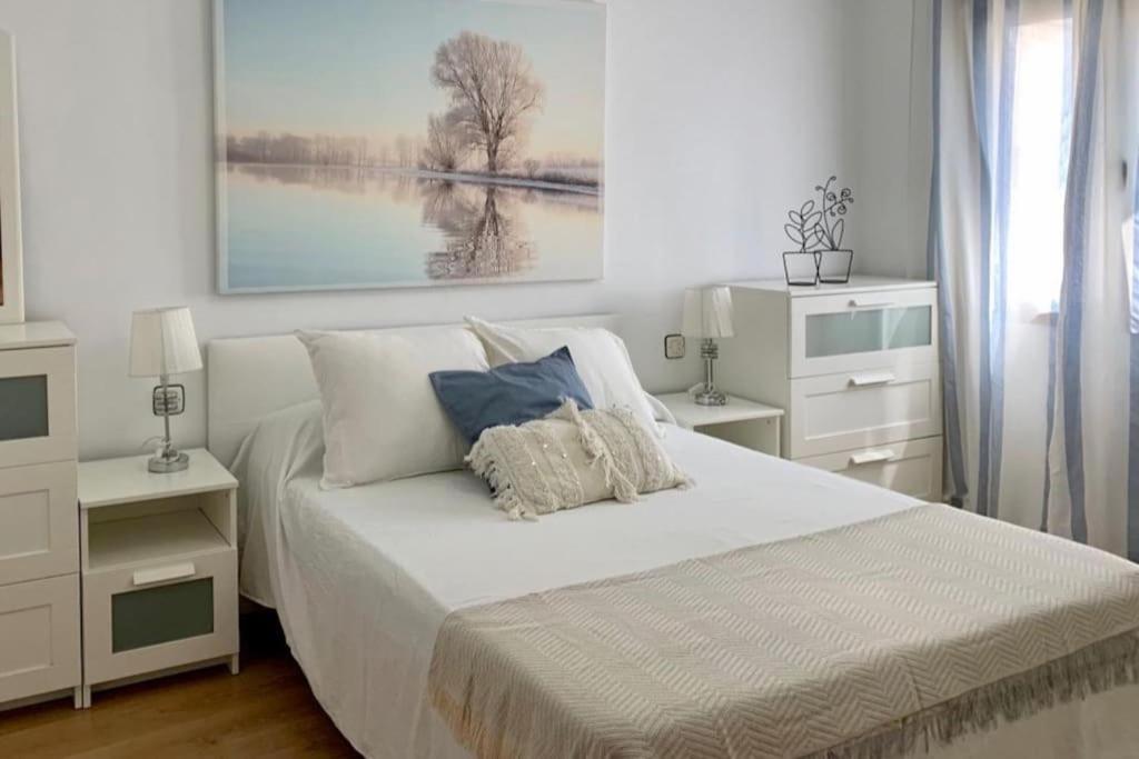 a white bedroom with a bed with a painting on the wall at La Casa de los Tiles in Vélez Blanco