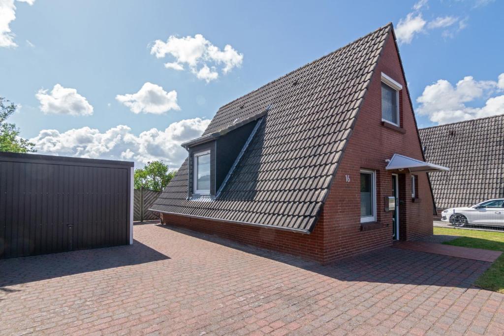 uma casa de tijolos com um telhado de gambrel em Spatzenhorst em Dornumersiel