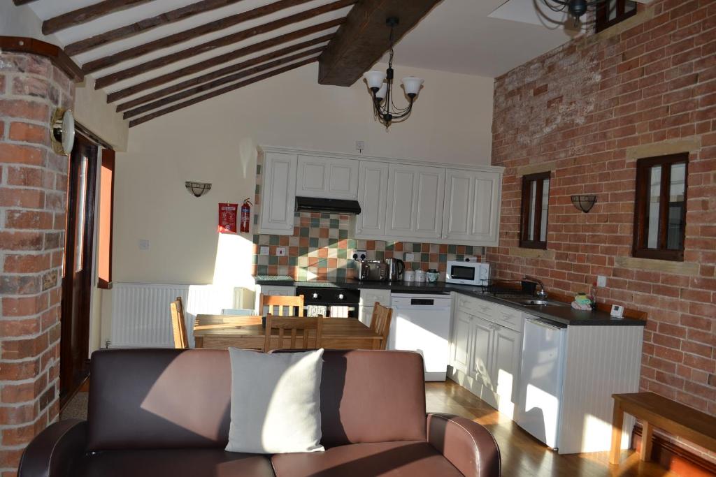 a living room with a couch and a kitchen at Lodge Barns in Fiskerton