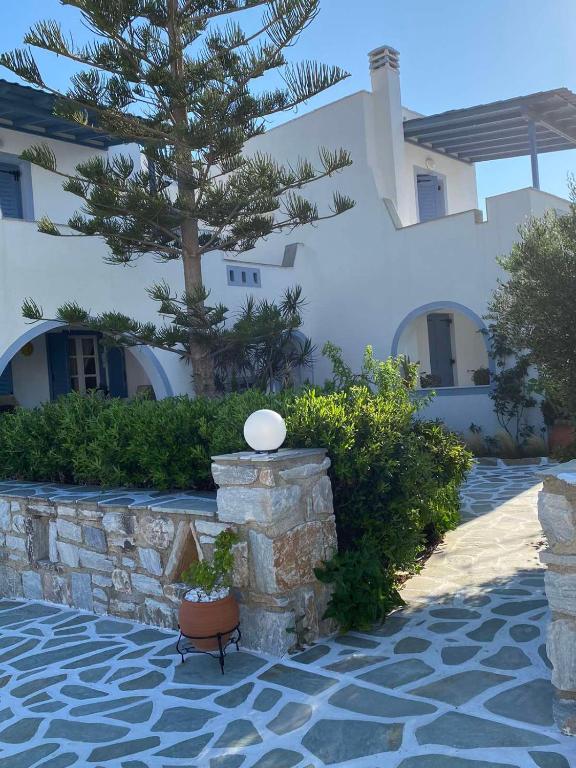 a building with a stone wall and a tree at Kapares Studios & Apartments in Agia Anna Naxos