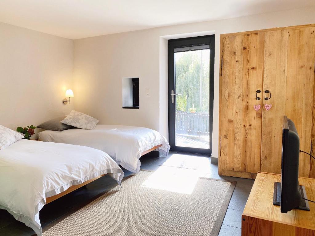 a bedroom with two beds and a tv and a window at La Petite Grange in Villars-sur-Ollon