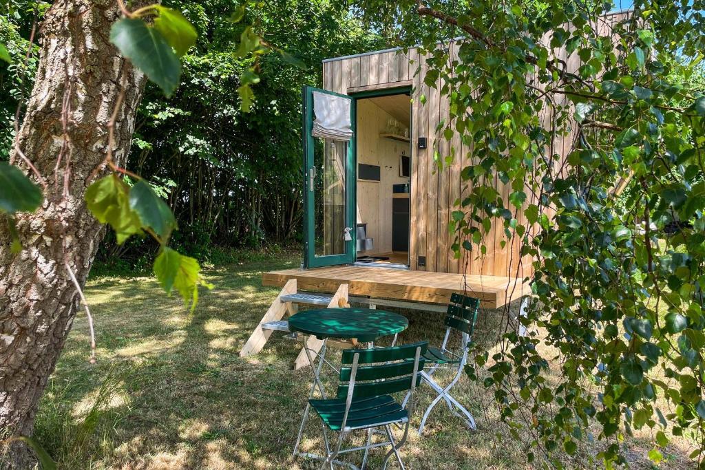 a tiny house with a table and chairs in the yard at Sleep Space 01 - Green Tiny Spot Geltinger Bucht in Steinbergkirche