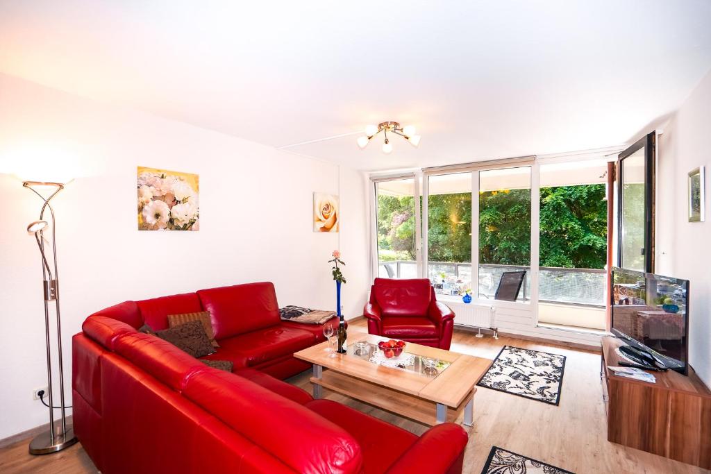 a living room with a red couch and a table at Fewo am Meer, mit Schwimmbad und Sauna in Timmendorfer Strand