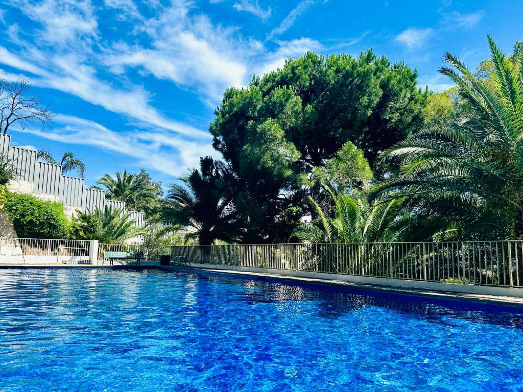 une piscine d'eau bleue et d'arbres dans l'établissement Luxury 130m2 AC, Terrace, Pool, Parking - Steps to beach, 5 min Palais des Festivals 3BR-3BA, à Cannes