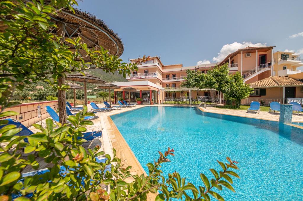 a large swimming pool with blue chairs and buildings at Kalias Hotel in Vasiliki