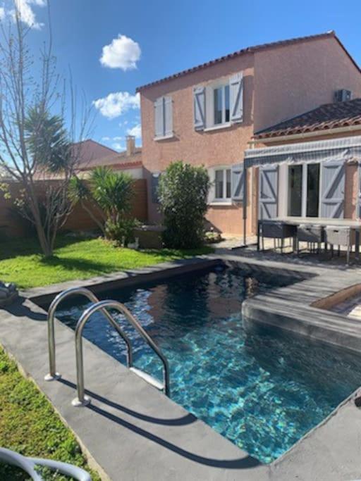 a swimming pool in front of a house at Charmante villa équipée, piscine in Le Soler