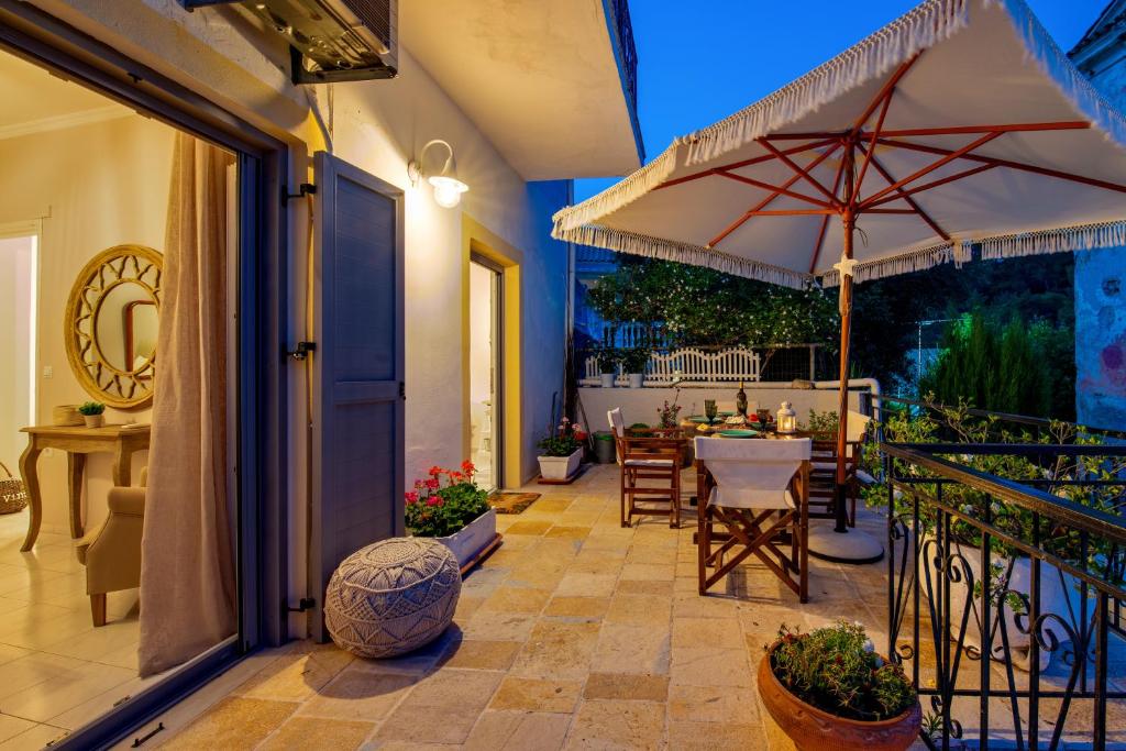 a patio with a table and an umbrella at Marilu's, Paxos Port House in Gaios