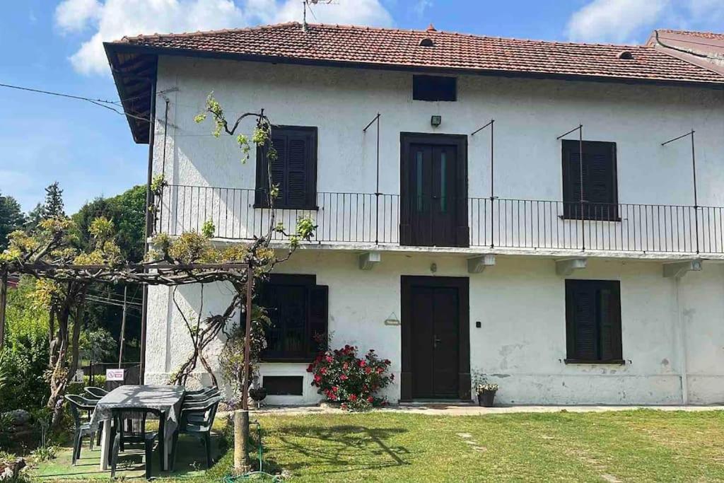 een wit huis met zwarte deuren en een tafel bij Cascina “La Bizzarina” in Castelletto sopra Ticino