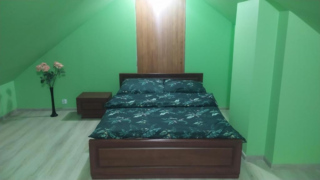 1 cama en un dormitorio con una pared verde en Grill nad Potokiem, en Grybów