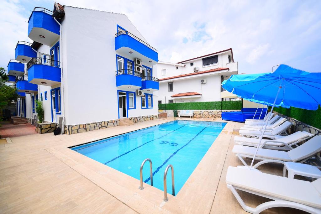 a pool with chairs and umbrellas in front of a building at Fethiye Apart Otel in Fethiye