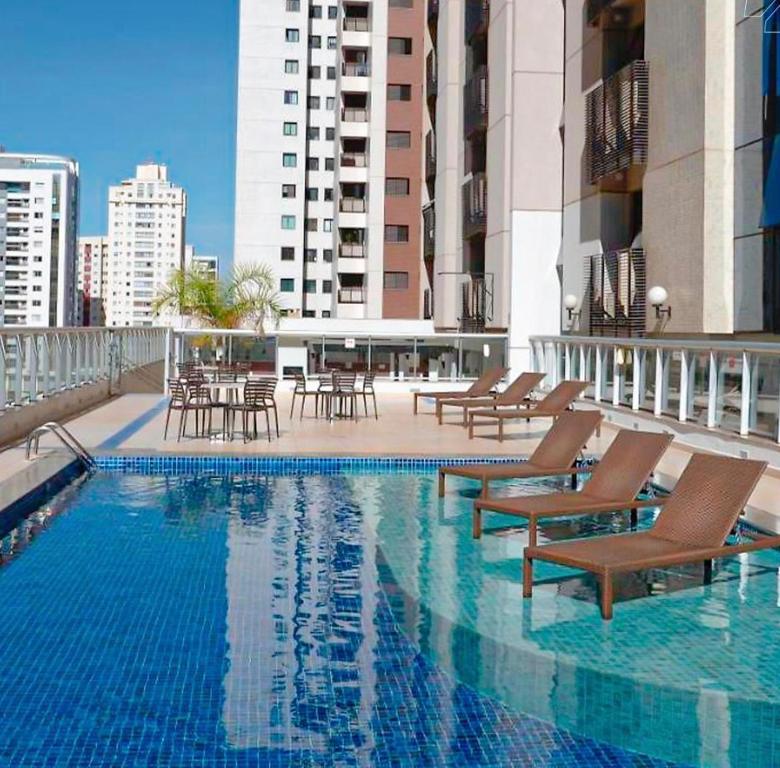 a swimming pool with chairs and tables on a building at Flat Aguas Claras 218 S4 in Brasília