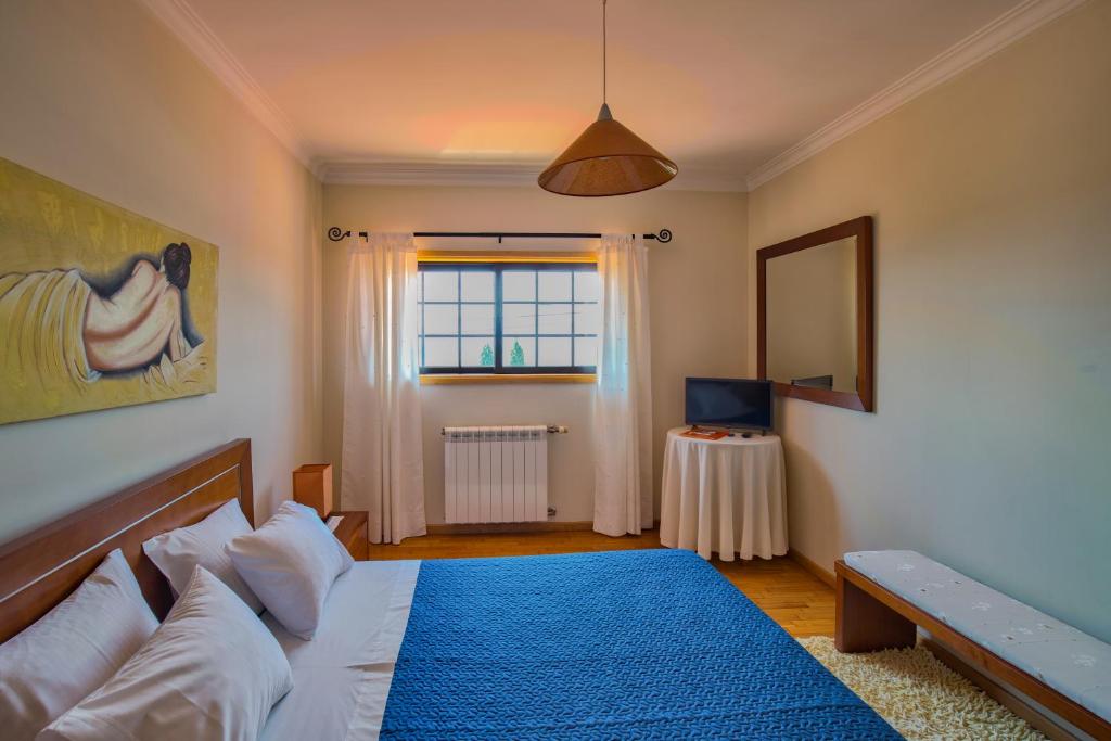 - une chambre avec un lit doté d'une couverture bleue et d'une fenêtre dans l'établissement Quarto em Viana do Castelo, à Viana do Castelo