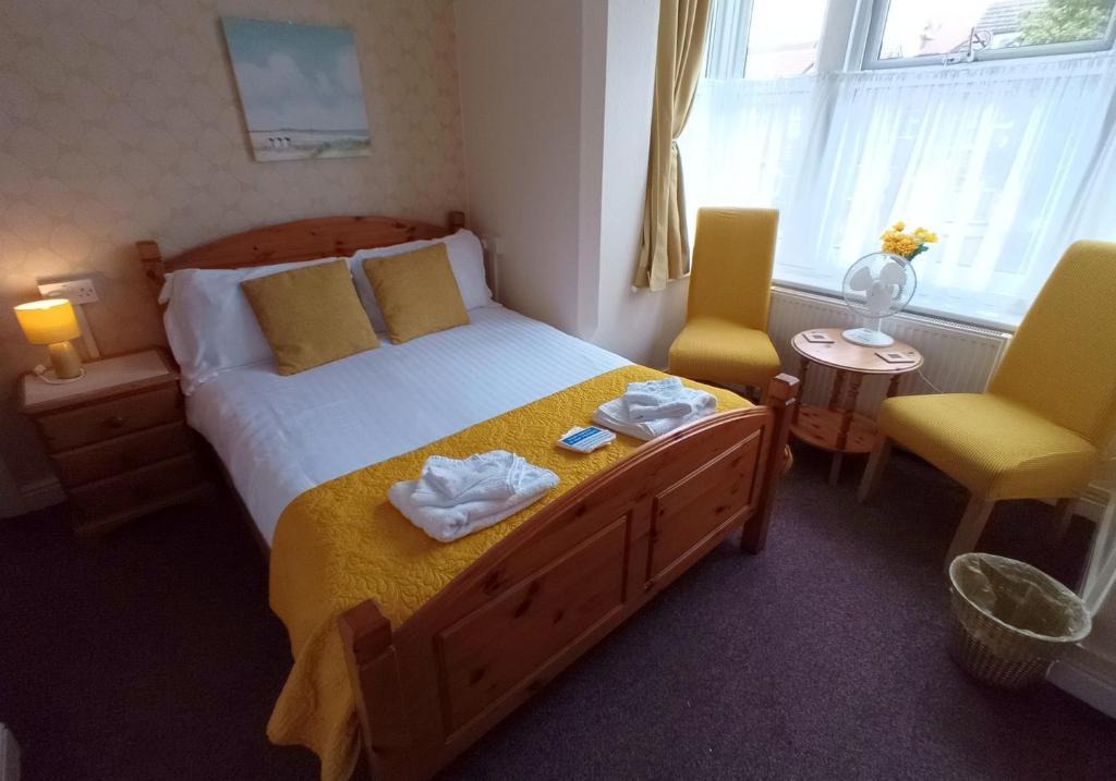 um quarto com uma cama grande e 2 cadeiras amarelas em Brackenhurst Guest House em Skegness