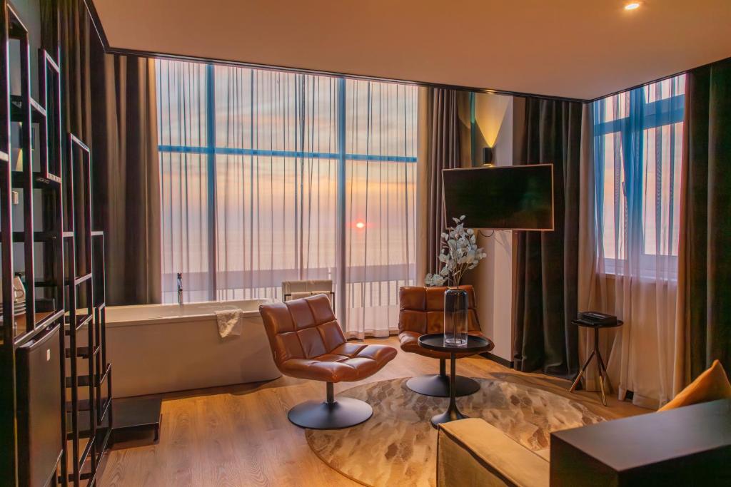 ein Wohnzimmer mit einem Sofa, einem Stuhl und einer Badewanne in der Unterkunft Palace Hotel Zandvoort in Zandvoort