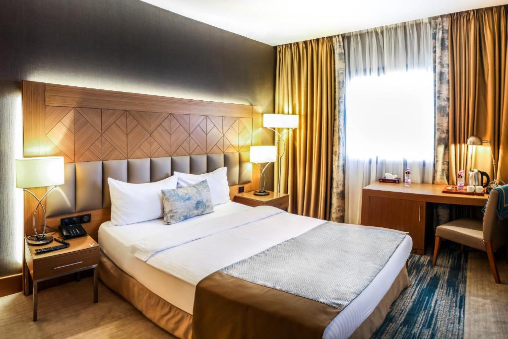 CheragaにあるSYM Hôtelのベッドとデスクが備わるホテルルームです。