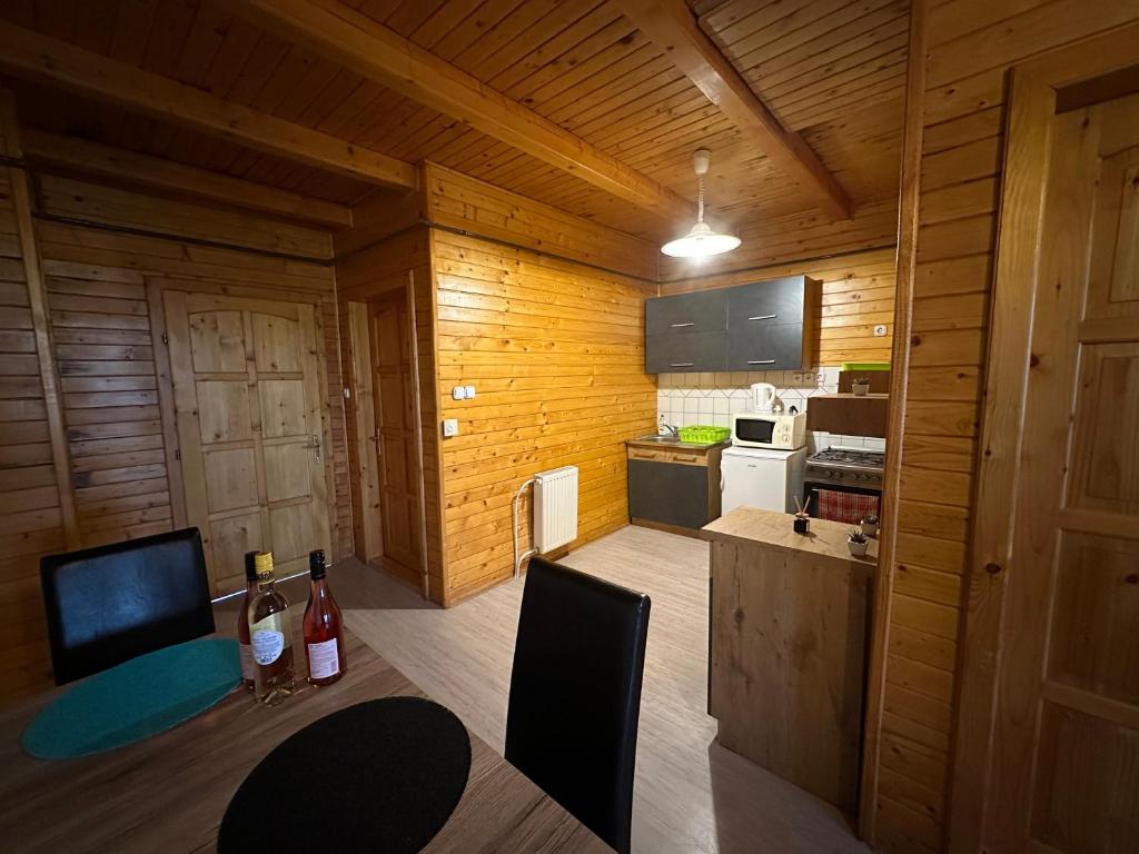 una cocina con mesa y 2 sillas y una cocina con botellas de vino en Virág Apartman, en Felsőtárkány